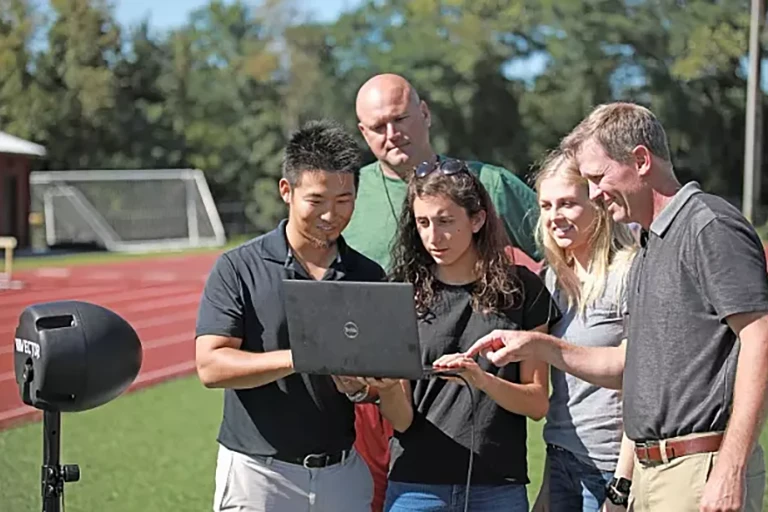 脑震荡研究人员Kei Kawata和他的同事们正在户外运动场上看着一台笔记本电脑.